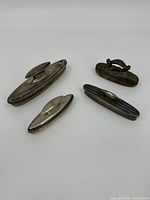 Four antique/vintage sterling silver nail buffers arranged together showing overall size and design variety.
