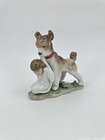 Front-left angle view of the Lladro figurine showing dog's face and child figure on the grassy base.