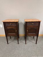 Front view of the pair of vintage side tables with stone tops, showing the drawers and cabinet doors.