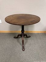 Front view of the vintage round wooden table showing the turn top design and tripod base.