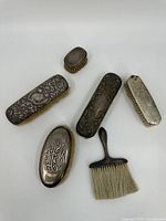 Overview of all six sterling silver vanity brushes showing various sizes and ornate engravings.