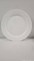 Front view of one white ceramic dinner plate with scalloped edge and subtle decorative pattern from Bormioli Rocco Ebro collection