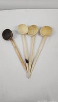 Four handmade wooden spoons laid out side by side showing bowls and handles, displaying natural wood color variations.