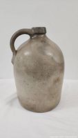 Full frontal view of the antique stoneware jug showing the body and handle.