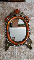Front view of oval mirror on stand showing ornate frame and reflective surface