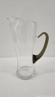 Full view of clear glass martini pitcher with smoked olive handle showing overall form and size.