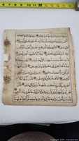 Full view of the manuscript page showing Arabic text and two circular seals on left margin with a measuring tape for size reference.