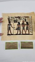 Full view of the hand painted Egyptian portrait on papyrus with four figures and hieroglyphics, and two green guarantee certificates below.