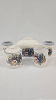 Front view of full ceramic tableware set: butter holder, sugar, creamer, salt and pepper shakers with hand-painted floral motif on cream ceramic.