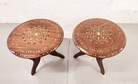 Overhead view of two round tables side by side showing inlaid floral medallion pattern