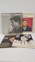Full view of 2 vinyl records and 2 magazines showing John F. Kennedy on all covers