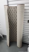 Rolled beige and brown diamond pattern carpet showing front and back side.