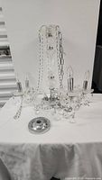 Full view of the vintage crystal chandelier showing the multiple arms with bulbs, metal hanging chain, and base plate on a white surface.