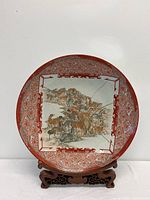 Full front view of the large circular Kutani charger on its wooden stand, showing painted horse scene and rim details.