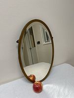 Front view of the vintage Brasscrafters oval mirror showing brass-colored frame and reflective surface.