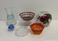 Full view of all six glass items on white surface with plain background. Includes two candy dishes, one comport, a signed perfume bottle and two vases.