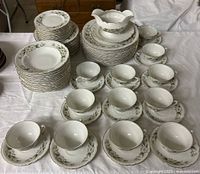 Full set displayed showing stacked plates, cups with saucers in front, and gravy boat centered on pile of plates.
