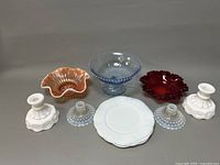 All items arranged on display including candle holders, plates, and colored glass dishes.