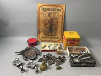 Full lot overview showing tins, brass and cast iron figurines, pewter salt shakers, and box for Oster hair clipper.