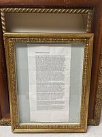 Three gilt ornate picture frames in a group, showing varying decorative patterns and sizes, one with a framed document.