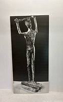 Full view of black and white poster showing bronze sculpture on a plain wall.