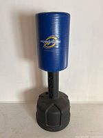 Full view of the blue Powerline free standing punching bag with black base against a white wall.