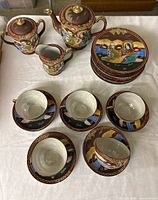 Full set layout showing 9 plates stacked, creamer, sugar bowl, teapot, 5 cups and saucers arranged on cloth
