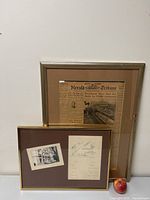 Framed vintage New York Herald Tribune newspaper article and separate framed autograph sheet with black and white photo and signatures.