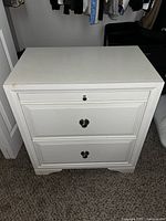 Front view of white wooden nightstand with two silver hardware handles and two drawers.