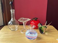 Lot of 5 glass art pieces shown together including decanter, blown flower vase, red apple, small swirled vase, and bird figurine