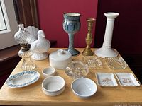 Full lot showing variety of vintage decor items on wooden table against red wall