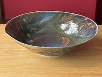 Side angle showing bowl's shape and glaze finish with blue, green and brownish-red tones.