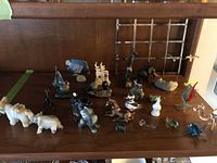 Overview of all animal figurines on wooden shelf showing various glass, marble, and ceramic animals representing elephants, horses, birds, deer, and others.