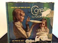 Box showing Corelle by Corning branding and image of mother and child holding dinnerware plates.