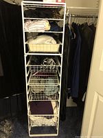 Two white Elfa shelving units shown side by side with folded clothing in baskets and on solid shelves. Wired basket shelves offer open storage.