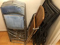 View of all 11 chairs stacked and folded showing metal frame padded chairs, wooden chair and wrought iron chairs.