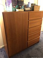 Front angle view of the chest showing five drawers on the right and cupboard door on the left with items on top.