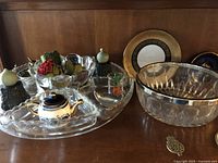 Photo of assorted glassware and ceramics including bowls and decorative items on wooden surface