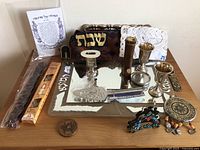 Overhead photo showing the entire lot with challah tray, fabric covers, candlesticks, kiddush cups, and other Judaica items arranged on a wooden surface.