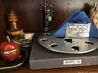 Initial photo showing on shelf an Emmanuel trivet, apple-shaped honey holder, a small Torah scroll decoration, and a napkin holder with Hebrew text on it.
