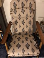 Front-facing view of armchair showing beige fabric with multicolor geometric pattern and attached lumbar cushion.