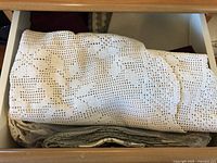 White crocheted tablecloth or napkins with rose floral pattern folded in a drawer