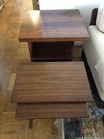 Side view of the larger rolling utility table with shelf, matching dark finish and scuffed surface.