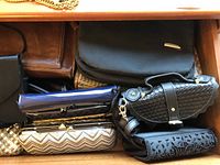 Various women's purses and clutches arranged in a drawer showing different styles and colors