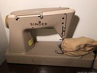 Front side view of beige Singer 500A sewing machine with cloth pouch on base.