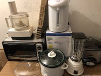 Photo showing Cuisinart food processor, Euro Pro toaster oven, Rival crockpot, Osterizer blender, electric thermo pot with box, and vintage warmer tray.