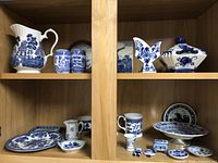 Shelf display of all traditional blue and white ceramic items showing a variety of pitchers, plates, mugs, and small decorative pieces.