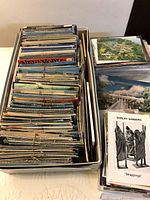 Large collection of bundled and loose vintage postcards in box and on table
