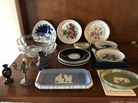 Overview of entire lot including Wedgwood jasperware dishes, floral plates, glass bowls, vase, and candelabra.