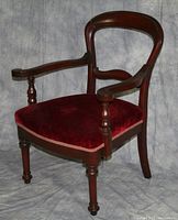 Front angle photo of one wooden armchair with red velvet upholstery, visible turned legs and arm supports, showing wear on varnish